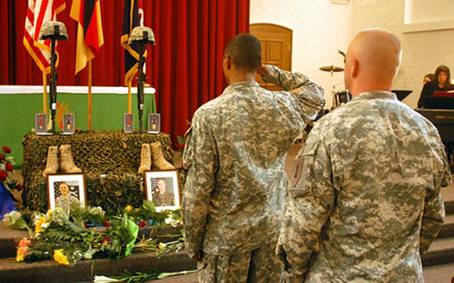 A soldier on salutes a memorial display for Sgt. 1st Class Raymond R. Buchan and Staff Sgt. Michael L. Ruoff Jr. during a service at Ledward Chapel in Schweinfurt, Germany. Buchan, of 1st Battalion, 18th Infantry Regiment, and Ruoff, of 1st Battalion, 77th Armor, were killed in combat in Ta&#39;meem, Iraq, on July 1.