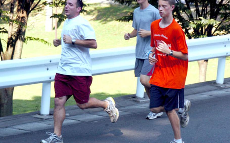 Beau Veazey, left, Yokota Middle School’s cross-country coach and the organizer for this week’s Kanto Plain Running Camp, runs with campers Adam Thomas and Jacob Sterry Wednesday at Tama Hills.