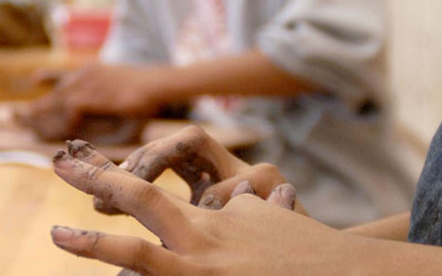 Aniyah Davis, an 11th grader at Kaiserslautern High School, wedges clay in preparation for sculpting in ceramics class March 12, 2007.