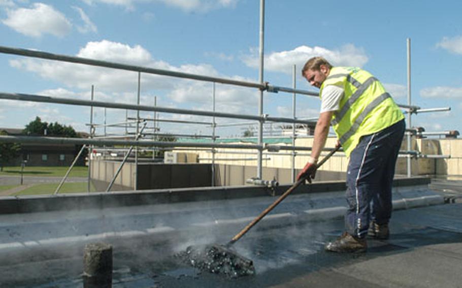 Scott Thurston, of Total Roofing Services, spreads hot tar on the roof of the Eagle&#39;s Landing building on RAF Lakenheath. This building and other Lakenheath facilities have had roof work done this summer, one of the wettest on record.