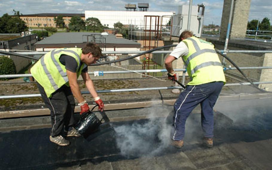 William Celentano, left, and Scott Thurston, of Total Roofing Services, spread hot tar on the roof of the Eagle&#39;s Landing building on RAF Lakenheath.