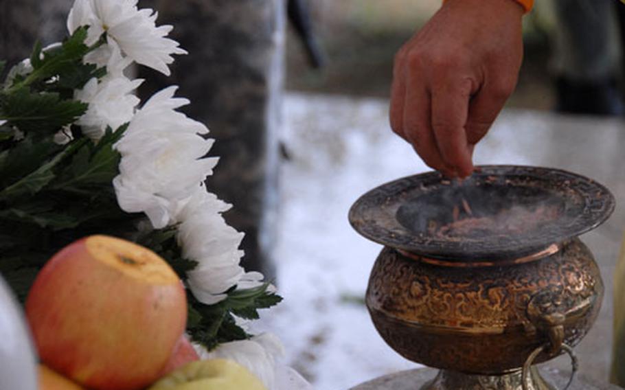 A South Korean drops incense into an urn during the ceremony.