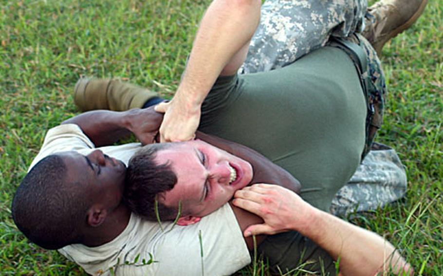 Spc. Terry Norman, with 58th Signal Battalion based on Fort Buckner, has a good hold from which Marine Cpl. Steven Sanders, with Marine Corps Base on Camp Foster, struggles to escape during a friendly competition in the field outside Gunner&#39;s Gym on Camp Foster, Friday.