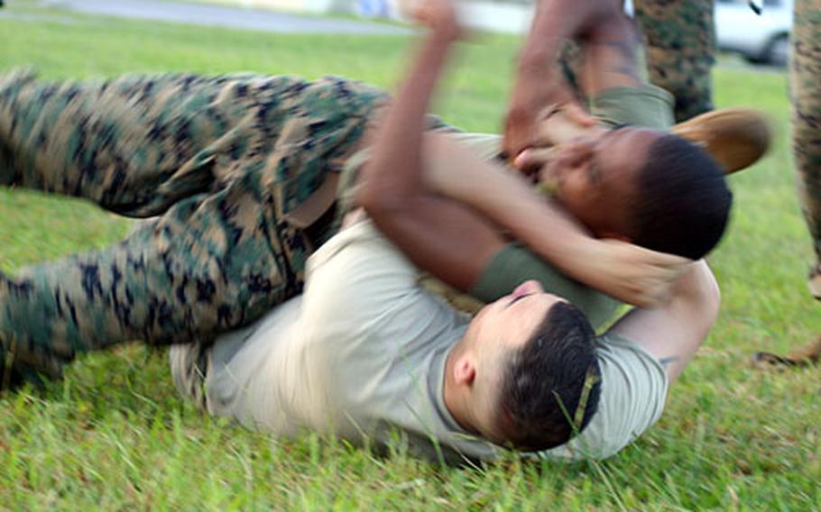 Marine Sgt. Anthony Richard, with Marine Corps Base, and Army Sgt. Peter Gonzalez, with 58th Signal Battalion based at Fort Buckner, roll along the ground struggling for dominance of the groundfight.