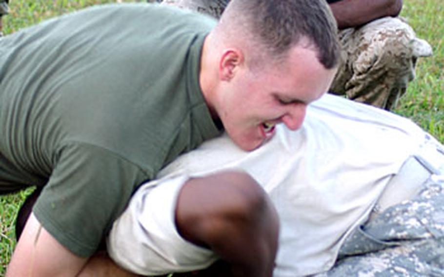 Sgt. Walter Perkins, a Marine Corps martial arts instructor trainer, watches as a Marine and a soldier grapple on Camp Foster as part of a friendly competition.