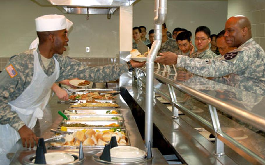 Pfc. Keith Collier, 1st Replacement Company, hands a plate to Sgt. Maj. Gary Fields, 2nd Infantry Division, during the grand reopening of the Camp Coiner’s dining facility.