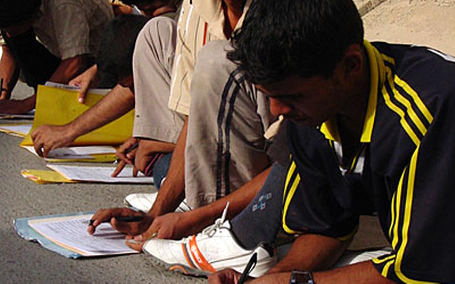 Iraqi police recruits complete their applications.