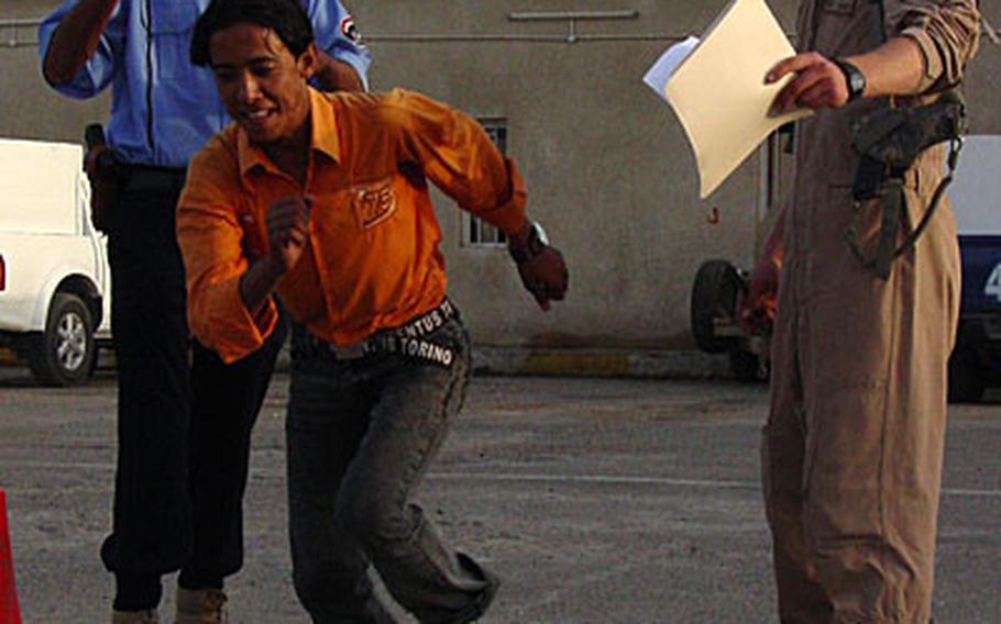 Air Force Senior Airman Justin Consley (right), an airmen with Detachment 3, 732nd Expeditionary Security Forces Squadron, and an Iraqi policeman (top left) time an Iraqi police recruit in the 100-meter run in Baghdad.