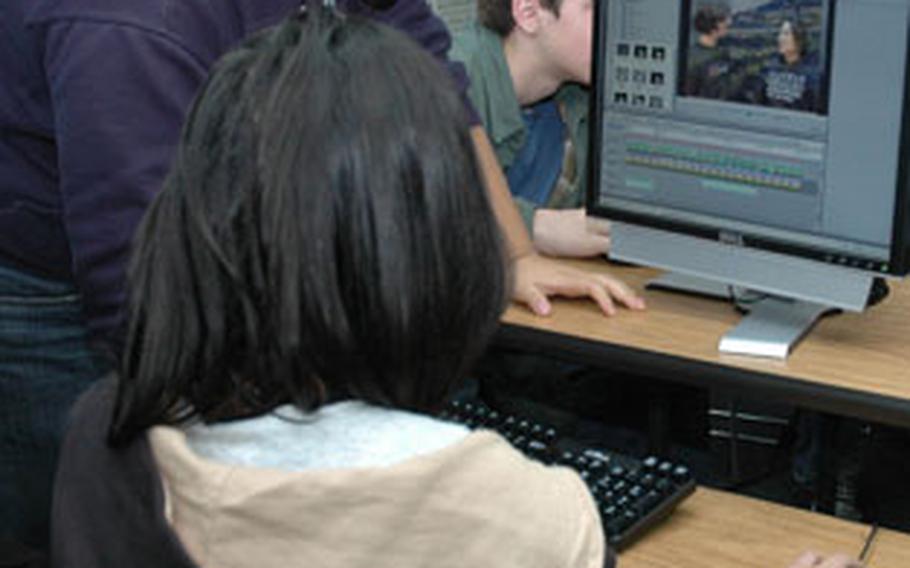 Erica Na (standing) looks at a video clip of herself doing a skit in Mandarin Chinese. Na and Christine Moon (seated) Worked on their project earlier this month during their Chinese II class at Seoul American High School.