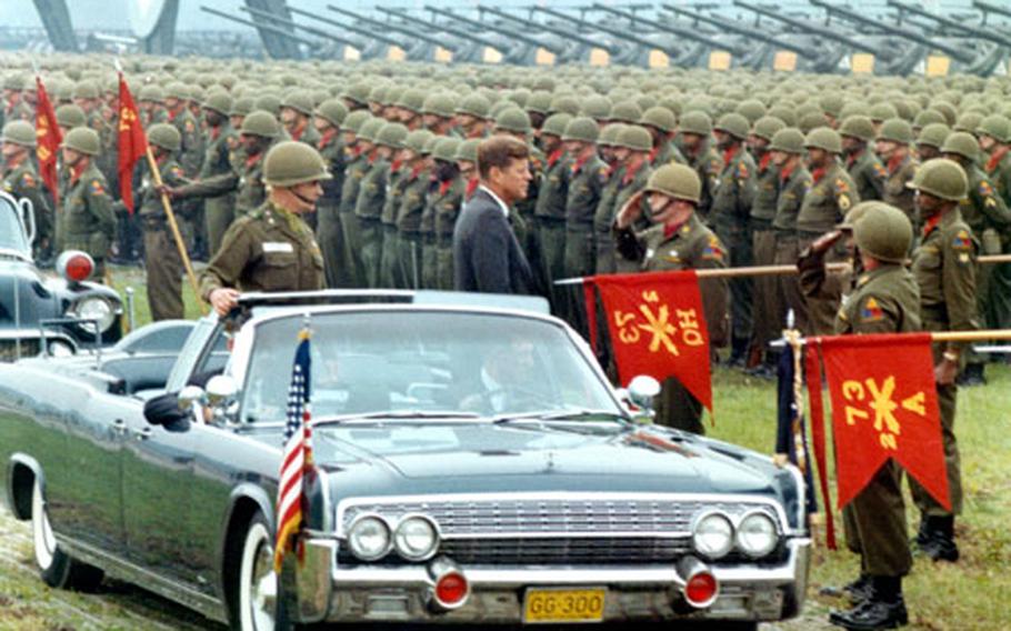 President John F. Kennedy stops to shake hands with Lt. Co. James Herman, commander of 73rd Artillery, as he and Maj. Gen. John Pugh, commander of 3rd Armored Division, troop the line at Fliegerhorst Kasern in Hanau, Germany, on June 25, 1963.