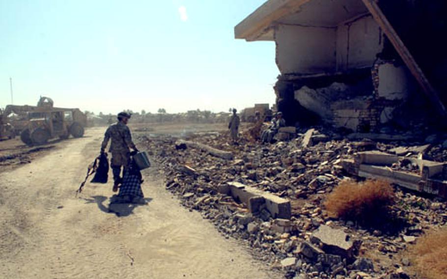 A soldier drags trash toward the burn pit as contruction gets under way at a new combat outpost southeast of Salman Pak.