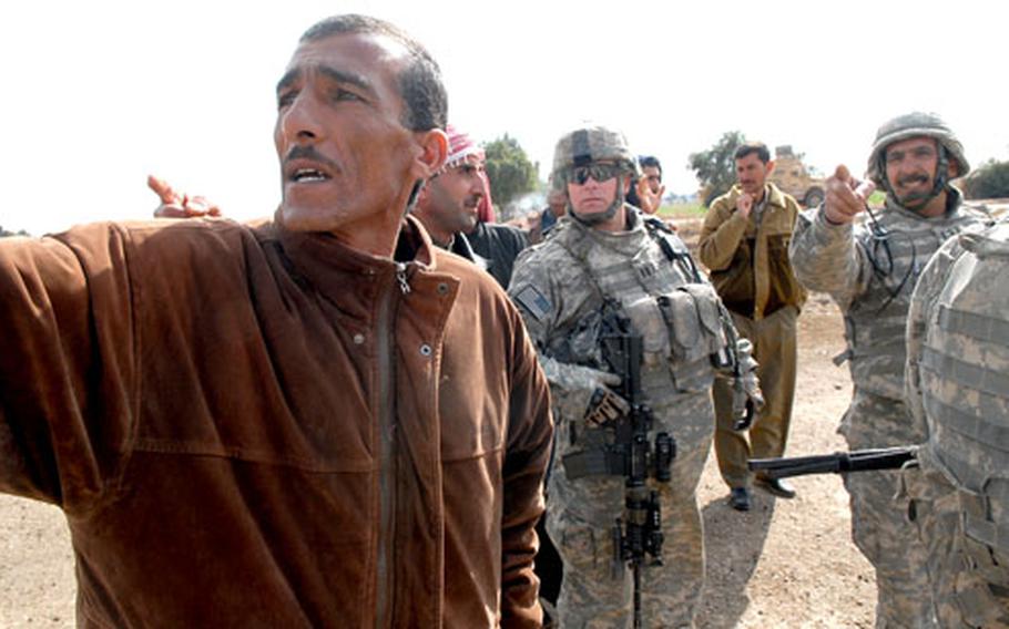 Army Capt. Rich Thompson, commander of Company B, 1st Battalion, 15th Infantry Regiment, listens as a group of men point to some buildings that they said al-Qaida had used as safe-houses before fleeing the area. Thompson and his soldiers are based at COP Carver, southeast of Salman Pak, Iraq, and are working with sheiks in the areato improve security.