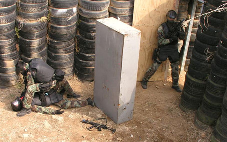 The SEAL on the ground is portraying a terrorist. They are wearing face masks for protection against the 9 mm paintball-tipped ammunition they fired.