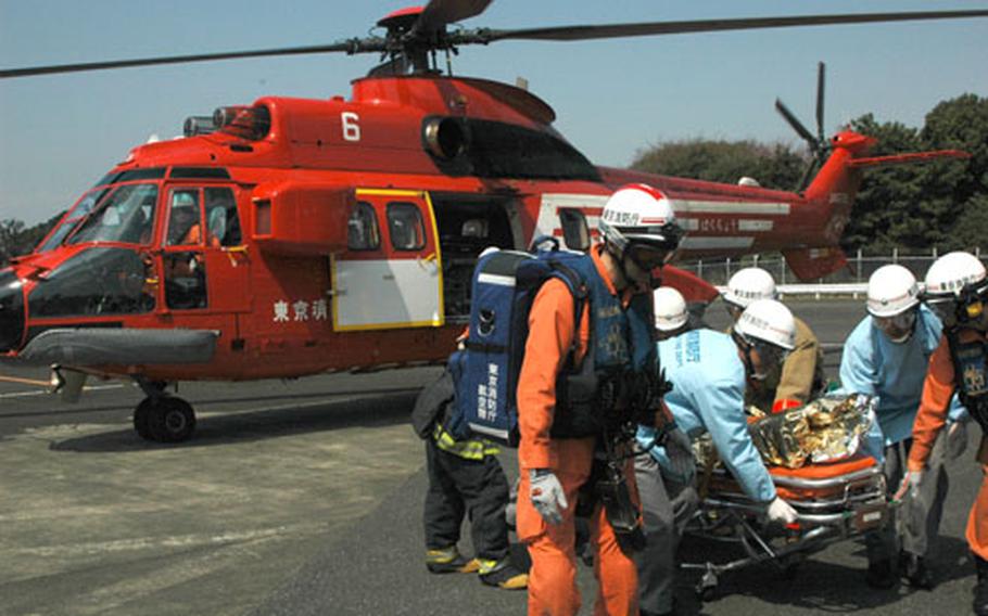 Tokyo Fire Department personnel carry a simulated patient out of a TFD helicopter during a training drill Wednesday at the Hardy Barracks heliport.