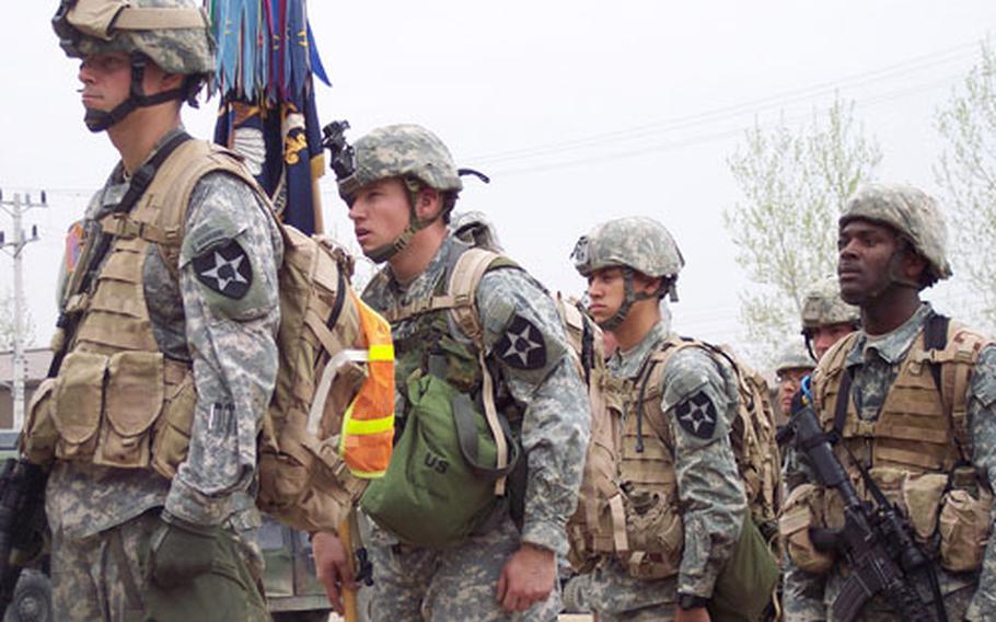 Soldiers from the lead group stand at attention as the regimental bell rings following their completion of the 25-mile Manchu Mile around Warrior Base, South Korea, on Tuesday.