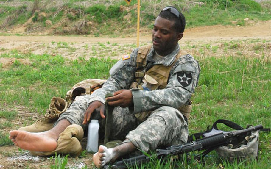 Pfc. James Roberts tends to his feet at the halfway point rest stop during the 25-mile Manchu Mile around Warrior Base, South Korea, on Tuesday.