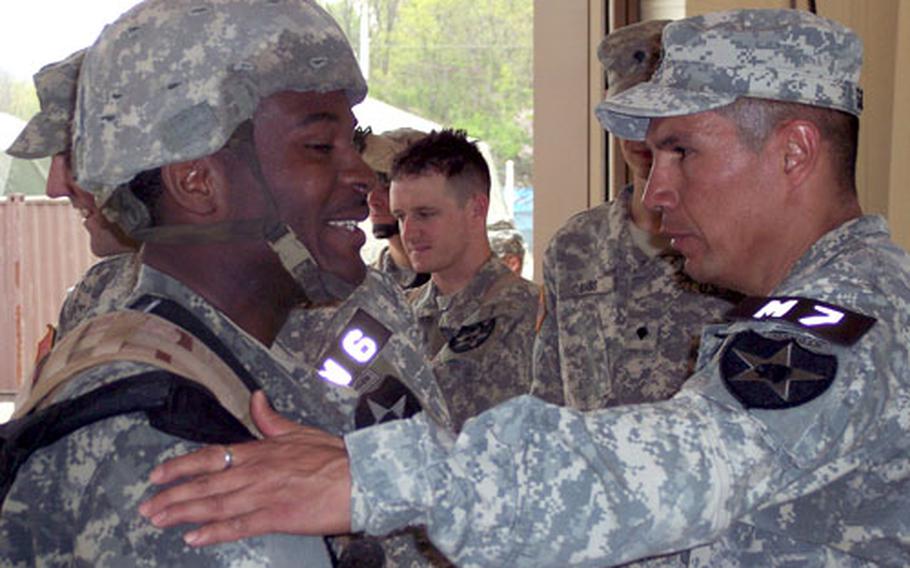 Pfc. James Roberts, of headquarters company, sniper section, is congratulated by Command Sgt. Maj. Bobby Gallardo upon finishing the 25-mile Manchu Mile around Warrior Base, South Korea, on Tuesday.