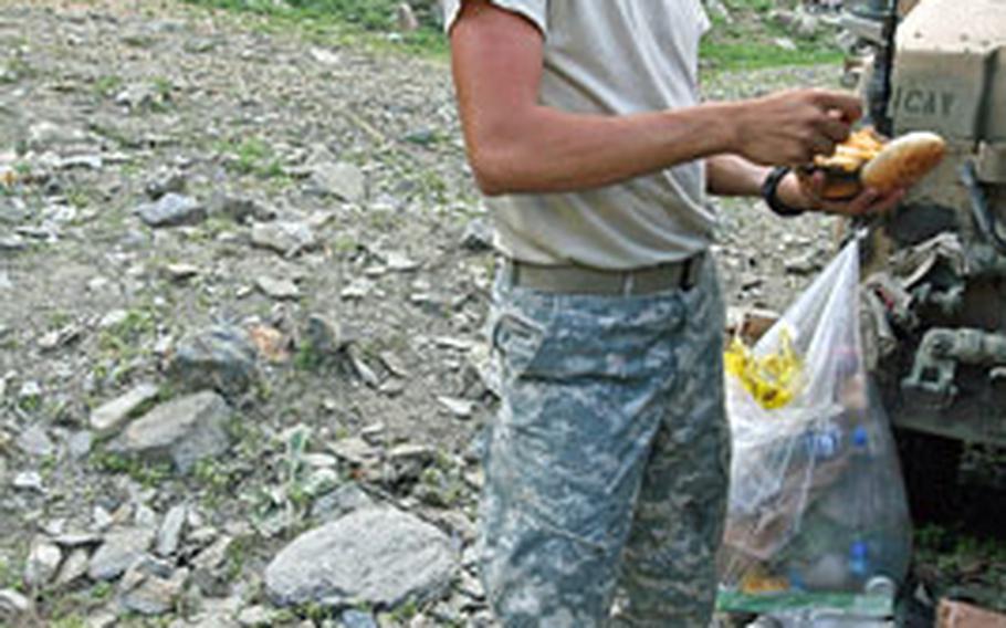 Pfc. Joshua Kiyoshi, 21, of Saipan, enjoys a hamburger fresh off the grill, a rare and welcome treat after days of nothing more than Meals, Ready to Eat.