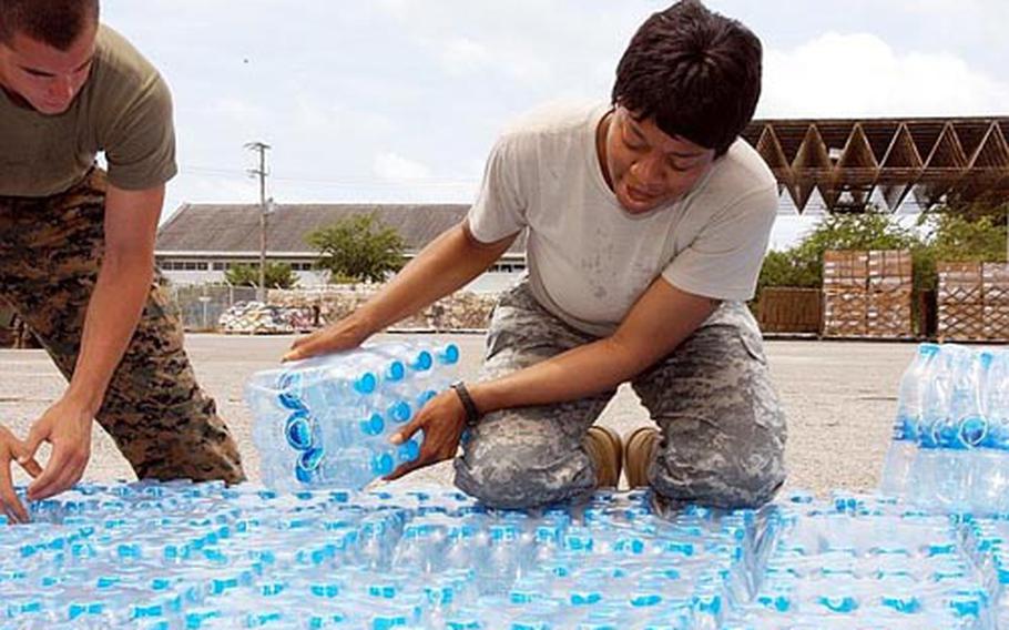 U.S. Army&#39;s Camp Zama SSgt. Jamelia Fritz, center, and Camp Kinser Marine Cpl. Stephen Clark, left, readied water for Myanmar Tuesday, as two more flights left from Utapao Air Base in Thailand.