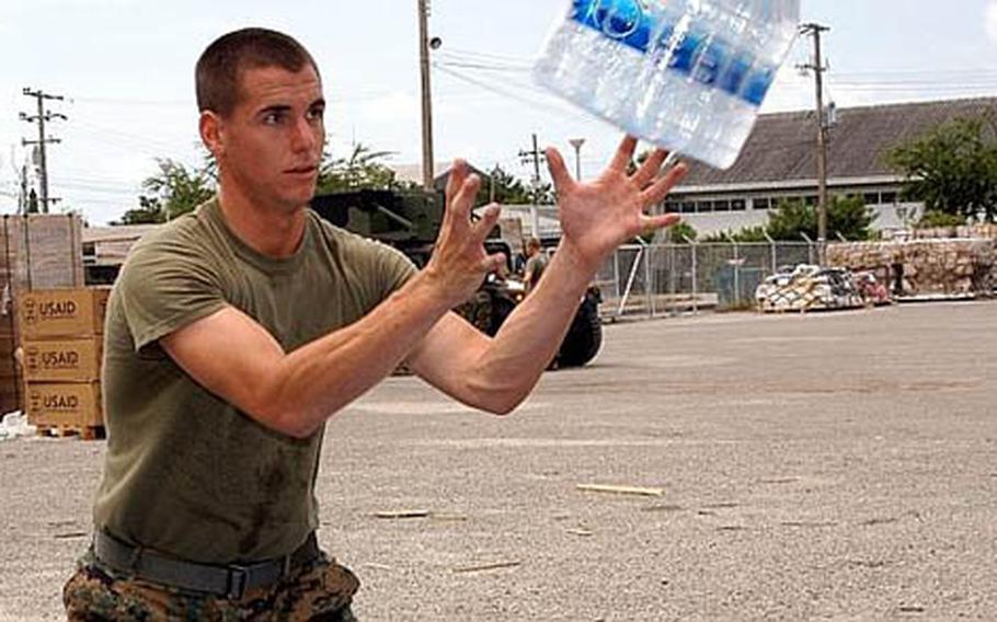 U.S. Marine Cpl. Stephen Clark, based in Okinawa&#39;s Camp Kinser, caught a case of water and packed it into 3,500-pound palettes for Myanmar Tuesday at Utapao Air Base in Thailand.