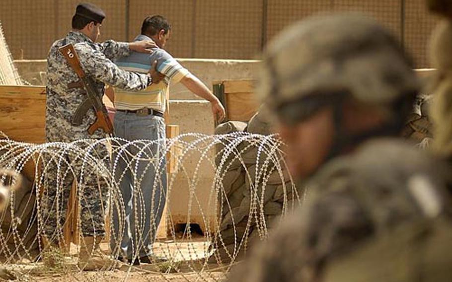 An Iraqi National Police officer searches a local customer Wednesday at the Joint Security Station in Jisr Diyala, Iraq. The JSS, staffed by U.S. Army and Iraqi National Police, is similar to a 911 center intended to help assist Iraqis with security and compensation claims.