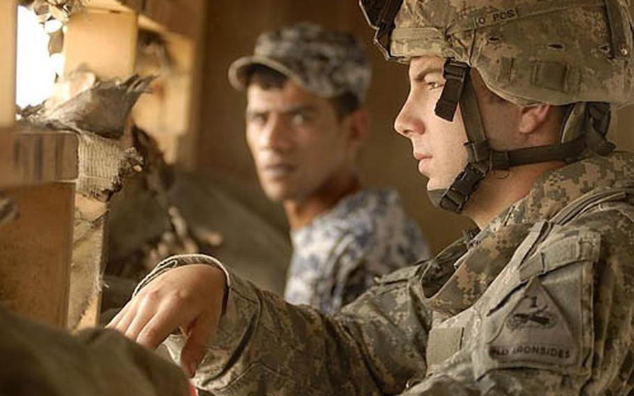 Pvt. Mark Wood, of Company B, 1st Battalion, 6th Infantry Regiment, stands watch in a lookout tower with an Iraqi National Policeman in Jisr Diyala, Iraq. The JSS, staffed by U.S. Army and Iraqi National Police, is similar to a 911 center intended to help assist Iraqis with security and compensation claims. 