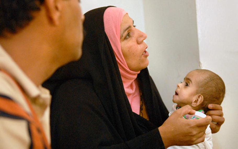 Huda Falih, holding her 7-month-old daughter Mariam, talks with Maj. (Dr.) Felix Oduwa, the doctor for 1-35 Armor, about the condition and care of her sick child Friday in Jisr Diyala, Iraq.