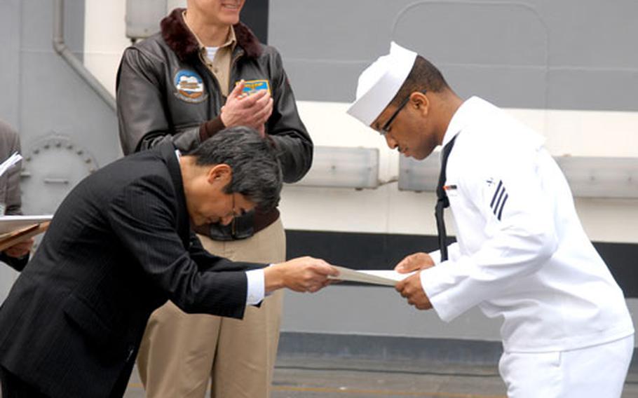 Kazuyuki Harada, left, a director of the Keihin Electric Express Train Company, thanks USS Kitty Hawk Seaman Phillip Simmons. Kitty Hawk&#39;s commanding officer Capt. Todd Zecchin, center, said Simmons&#39;s selfless act exemplified "the highest caliber" of Navy sailor.