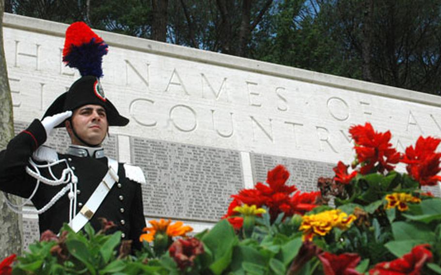 A member of Italy’s carabinieri renders a salute Monday during the playing of the U.S. and Italian national anthems. Behind him is a memorial with the names of 1,409 U.S. servicemembers missing in the fighting in Italy during World War II.