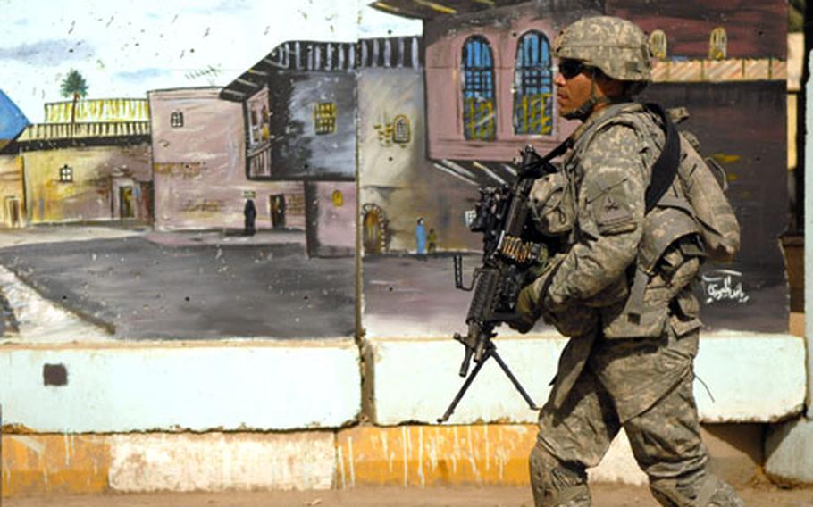 Spc. Olen Jessie, a soldier from Company C, Task Force 2-6 Infantry, marches past a mural on Salman Pak’s market street Friday during a patrol.