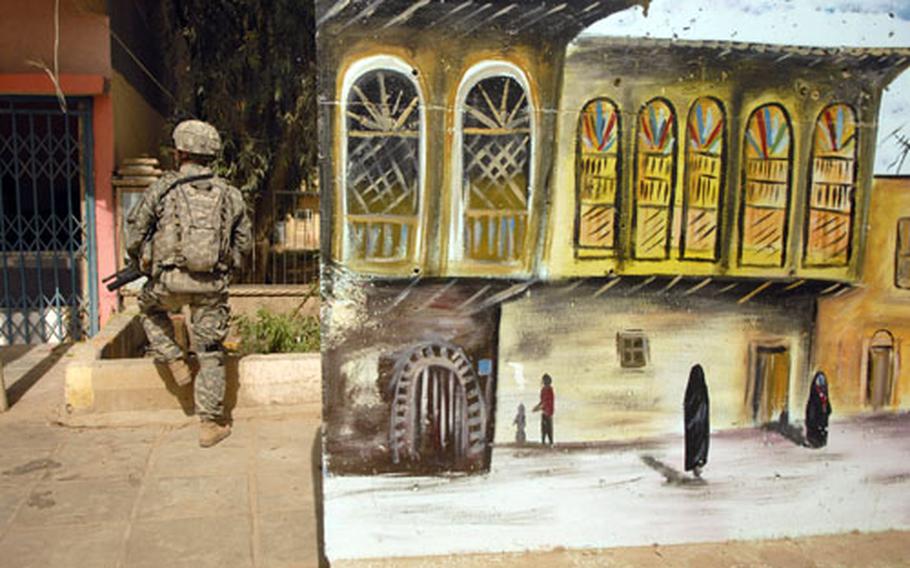 Pfc. Richard Moffitt, a soldier from Company C, Task Force 2-6 Infantry, pulls security during a patrol Friday in Salman Pak’s market street, near concrete barriers adorned with murals.