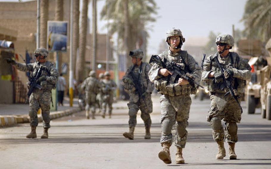 1st Lt. Thomas Schlichter and Spc. Allen Lee, both soldiers from Company C, Task Force 2-6 Infantry, patrol down Salman Pak’s market street Friday.