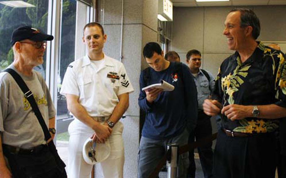 Retired Chief Warrant Officer 3 Darrell Blythe, far left, talks with Cutler Dawson, far right, the Navy Federal Credit Union president and CEO, when Dawson visited Yokosuka Naval Base, Japan, on Friday.