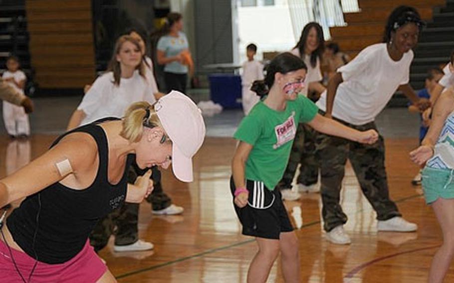 Casey Snyder, left, a fitness coordinator with Marine Corps Community Services, leads the fitness demonstration “Hip Hop with Casey” at the Fit Family Fun Day in the Camp Foster, Okinawa, field house on Saturday. Several events were designed to encourage parents and children to play together.