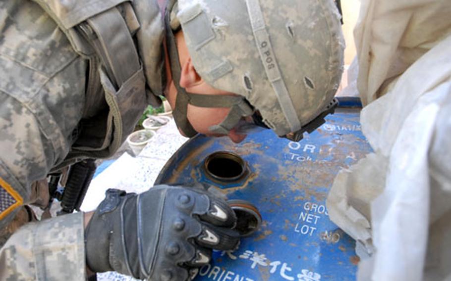 Sgt. Christopher Sherman cautiously sniffs an oil barrel Saturday at a home along the border of Mosul’s 17th Tamooz and Al Kubra neighborhoods. Insurgents sometimes hide homemade explosives inside oil barrels, so Sherman thumped the side of the barrel, peered inside and sniffed it to make sure that it really did contain oil.