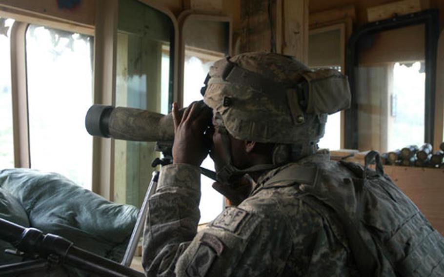 Spc. Corey McRae looks out a telescope to try to pinpoint a spot where he thought there might be some insurgent activity. Soldiers from 3rd Platoon man the towers around their small outpost around the clock.