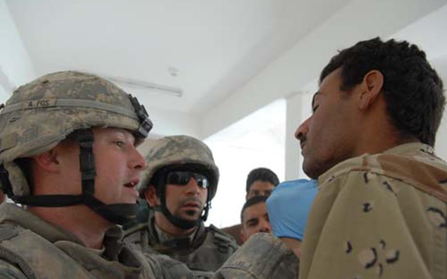 Sgt. Michael McAlhaney, a medic with Heavy Company, 3rd Squadron, 3rd Armored Cavalry Regiment, examines a cut on an Iraqi Army soldier’s chin Sunday in Mosul after being told that the soldier had an accident.