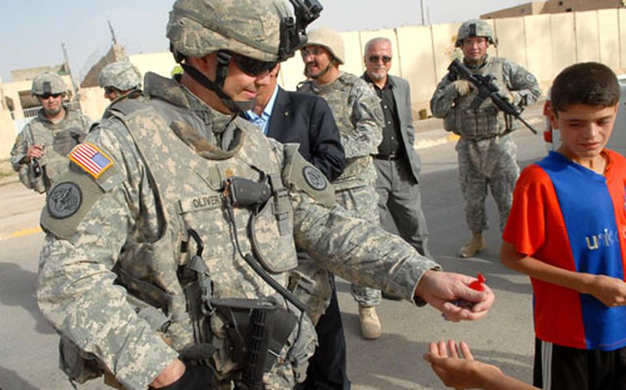 Maj. John Oliver, who is temporarily in charge of the 3rd Armored Cavalry Regiment units around Tal Afar, hands out candy to children while patrolling the city Tuesday.
