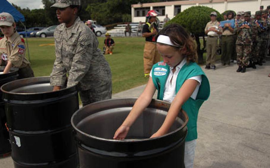 Shaina Franklin, 8, of Girl Scout Troop 445, places an unserviceable flag in a bin. Shaina was among dozens of local Girl and Boy Scouts who participated in the retirement ceremony.