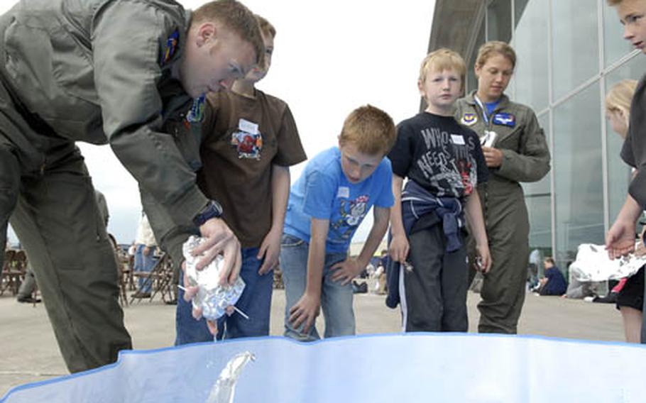 Capt. .Brad Caywood, with the 492nd Fighter Squadron at RAF Lakenheath, helps Suffolk-area children build tin foil boats Friday at the American Air Museum in Duxford. Caywood was one of 200 volunteers from the base who helped out at the event for kids who live near RAFs Lakenheath and Mildenhall.