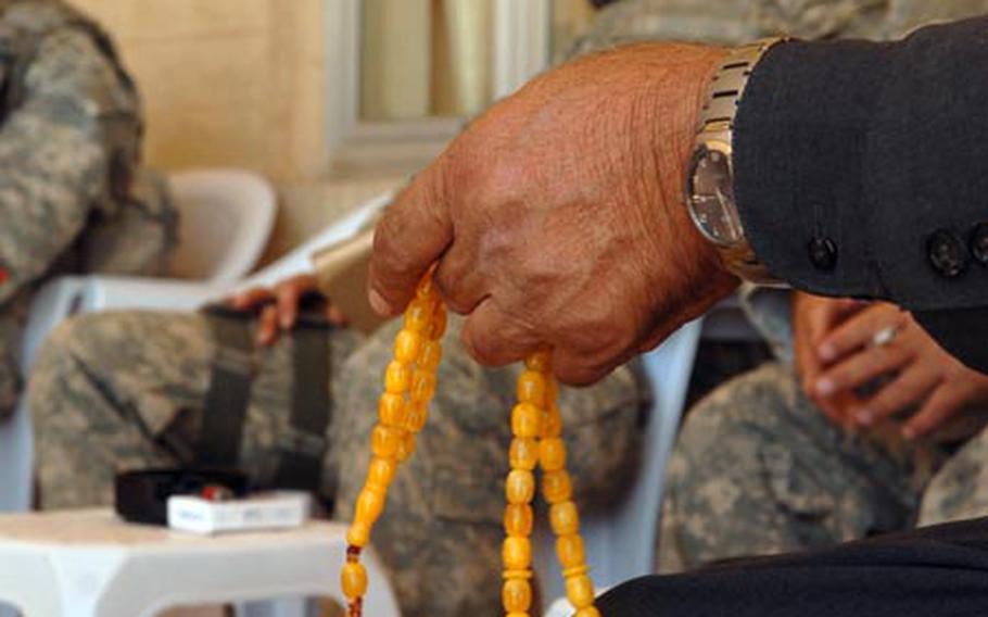An Iraqi man fingers a string of prayer beads Wednesday in Mustantiq, Iraq, while listening to his village head tell the American soldiers about a clinic that needs renovated. Small villages like Mustantiq lack even the most basic services found in larger cities.