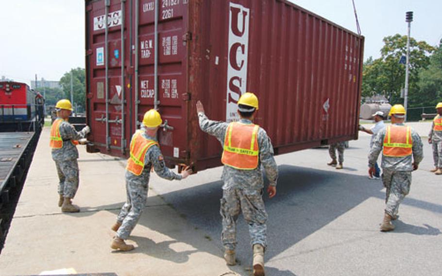 Soldiers from the 551st Inland Cargo Transfer Company guide a cargo container to the ground after a crane removes it from a train Friday at Yongsan Garrison.