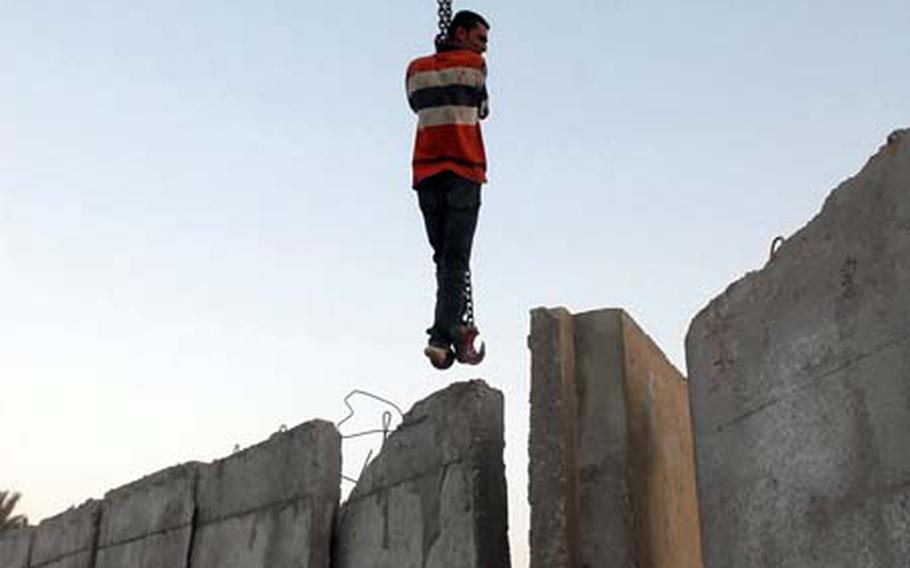 An Iraqi worker descends from atop a security wall being built around the Hurriya neighborhood in northwest Baghdad. U.S. officials say such walls have contributed to improving security in other parts of the capital.