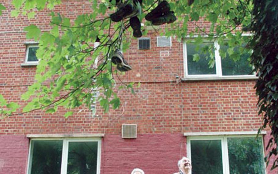 Jean Taylor, left, and Jack Wernette admire a tree behind the male dormitory that is decorated with at least 50 pairs of shoes left by departing students. Taylor and Wernette were on a tour of the vacant London Central High School campus, where they once worked.