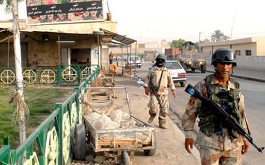 Iraqi troops pass a poster memorializing fallen Jaish al-Mahdi fighters in Shula.