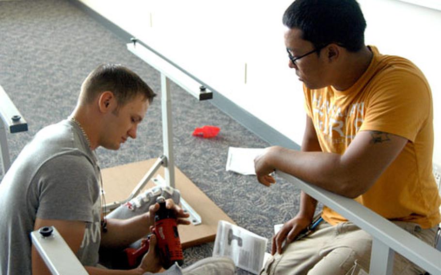 Airman 1st Class Atrayal Hale, left, and Airman 1st Class Andrew Failano, both of the 18th Civil Engineer Squadron, assemble desks inside a classroom at Ryukyu Middle School. The servicemembers volunteered to help set up the school.