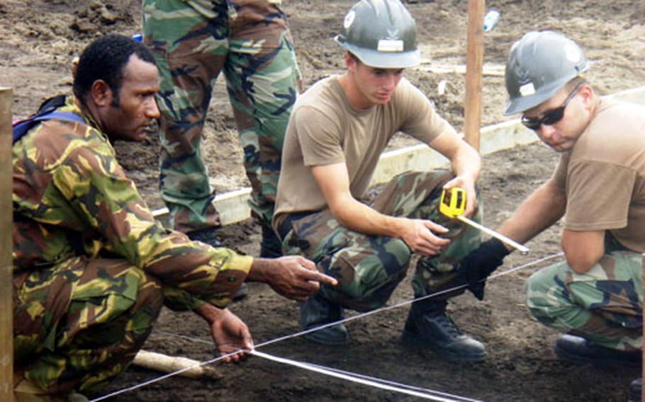 Petty Officer 2nd Class William Mills, center, a utilitiesman, and fellow crewmembers from U.S. Naval Mobile Construction Battalion 133 work alongside personnel from the Papua New Guinea Defense Force Engineering Battalion on the Popondetta General Hospital water system upgrades.