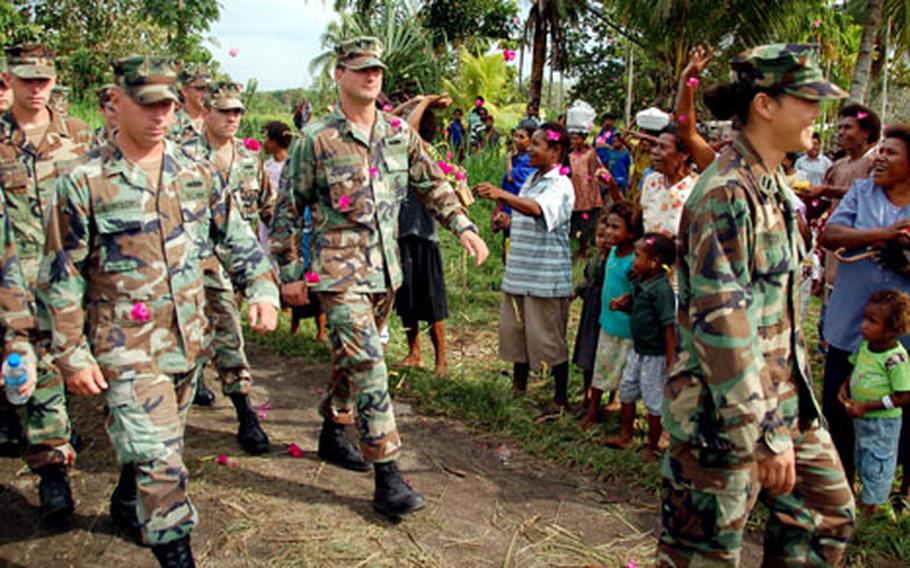 As U.S. Navy Seabees march to the Isivini Secondary School building, they&#39;re greeted with a shower of flowers by villagers in Popondetta, Papua New Guinea.