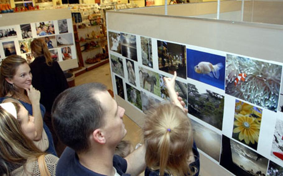 Visitors check out the contest photographs on display Friday evening in the Arts & Crafts Center at Yokota Air Base, Japan. Nearly 300 entries adorned the display, which was suspended from the ceiling.