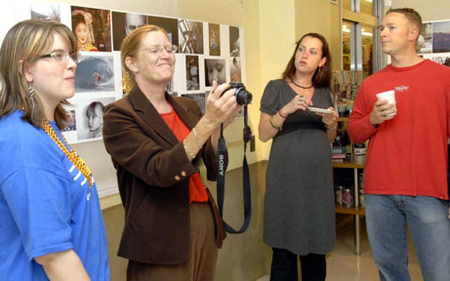 Mary Labdon, second from left, photographs the contest entries of her daughter, Alisha, left, on display Friday evening in the Arts & Crafts Center at Yokota. Alisha, 17, a senior at Yokota High School, won first place in the Scenic Nature category.